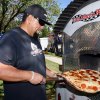 Steve Gonzalez of Fatte Alberts Pizza takes a pie from the oven during the Central Valley Pizza Festival on Sunday.